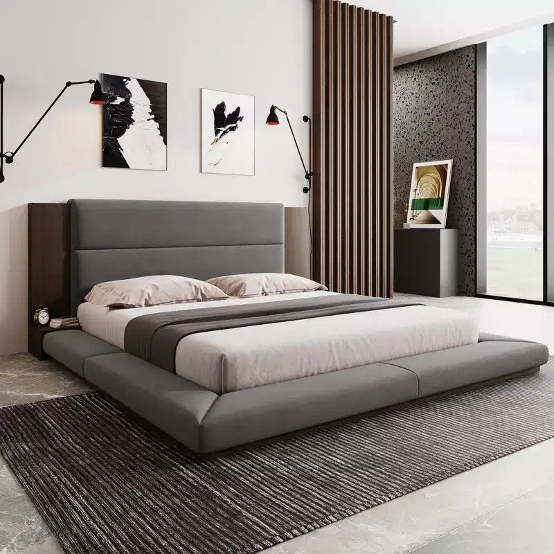 Letto imbottito a piattaforma, a filo pavimento, con testiera estesa in legno e mensole comodino integrate
